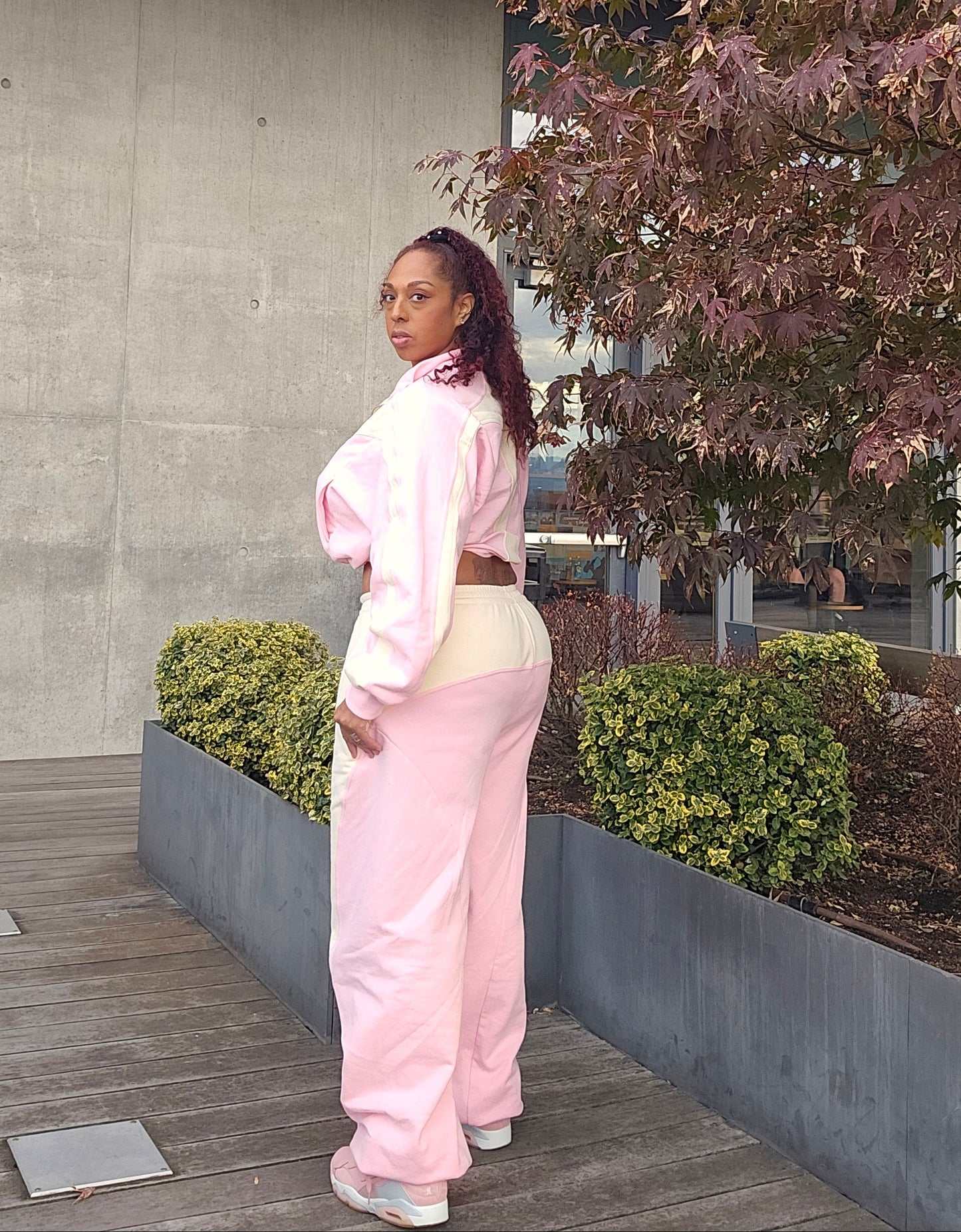 Person wearing a pink outfit standing on a stone path with trees in the background