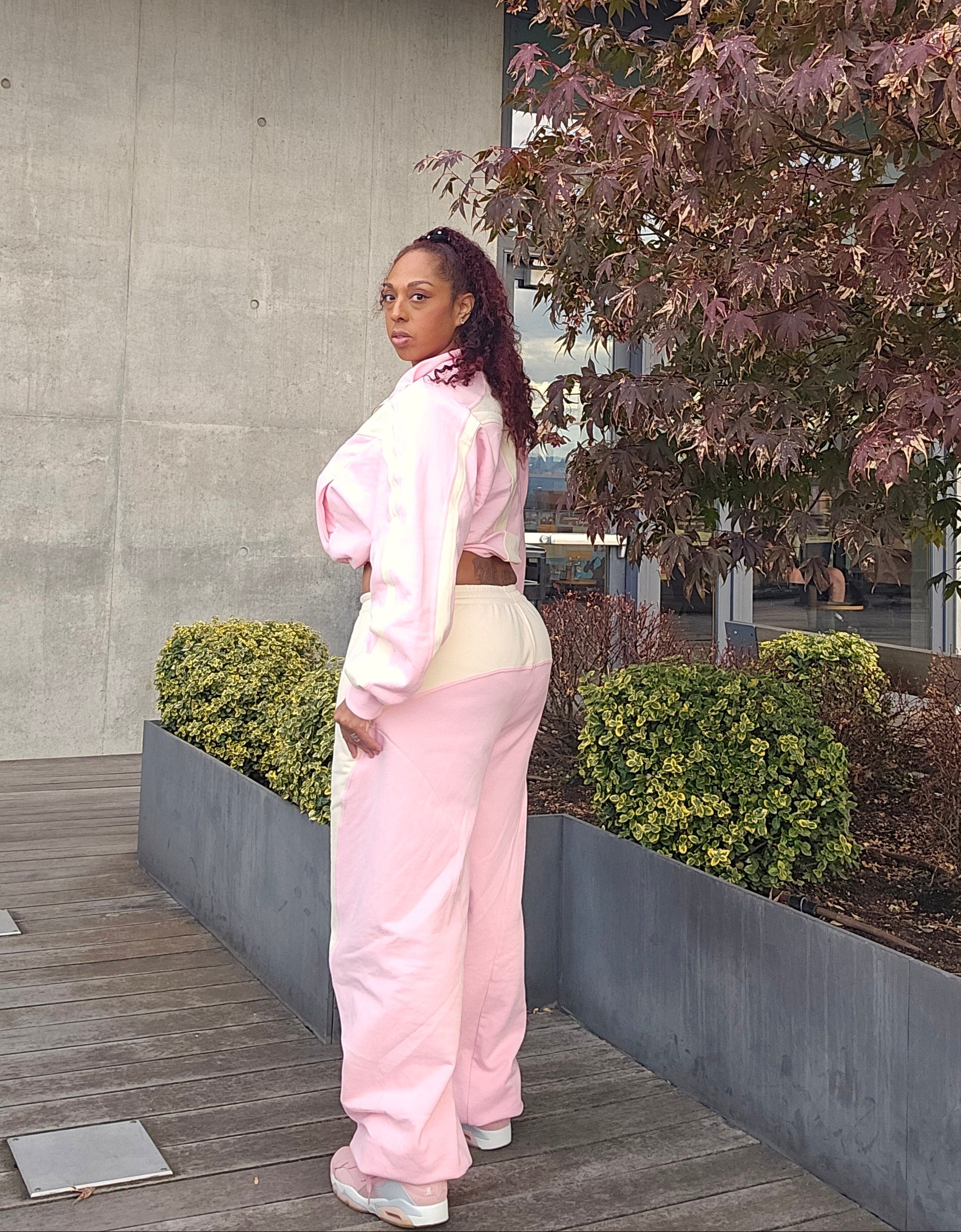 Person wearing a pink outfit standing on a stone path with trees in the background