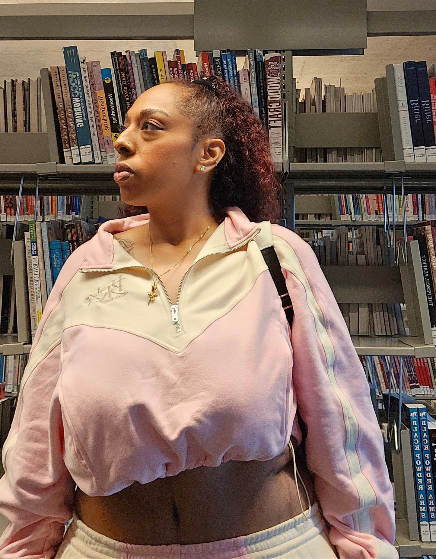 Person wearing a pink sweatshirt in a library setting